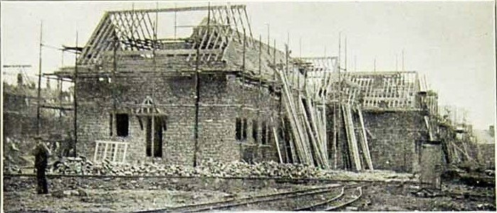 Construction of houses with scaffolding and workers at Well Hall Station